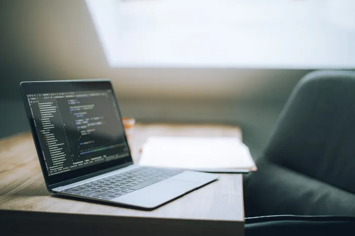 Laptop mit Quellcode auf einem hellen Schreibtisch
